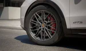 Zbliżenie na koło Porsche Cayenne GTS z czerwonymi zaciskami hamulcowymi i felgą w ciemnym kolorze.