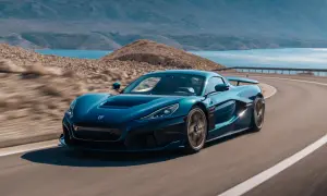 Niebieski Rimac Nevera sunie po krętej drodze nad turkusowym morzem, otoczony skalistym krajobrazem.