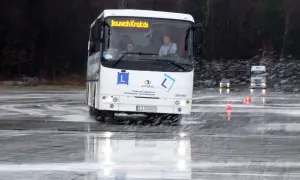 Autosan Lider Midi na mokrym placu manewrowym, z widocznymi kierowcami w kabinie.