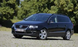 Czarny Volkswagen Passat kombi, model r36, zaparkowany na kamienistym podjeździe, z zielonymi drzewami w tle.