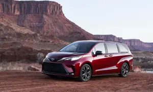 Czerwony minivan Toyota Sienna Hybrid na tle pustynnego krajobrazu z klifami.