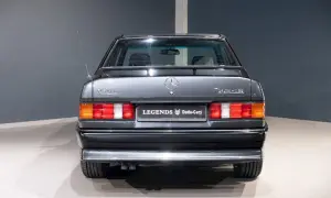 Tył szarego Mercedesa 190 2.5-16 z lat 80. z antenką i emblematami.