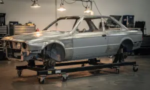 Karcass BMW E30 na wózku warsztatowym, gotowy do renowacji. Marzenie o **prawie jazdy a2** i własnym aucie zaczyna się od takich projektów.