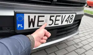 Palec wskazuje hologram na tablicy rejestracyjnej auta. Cały proces rejestracji auta zakończony sukcesem.
