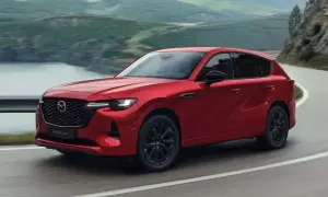 Czerwona Mazda CX-60 3.3 diesel na krętej drodze z widokiem na góry i jezioro.
