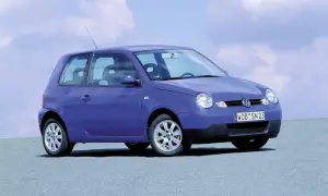 Fioletowy Volkswagen Lupo z tablicą rejestracyjną WOB SN 23 stoi na szarej nawierzchni pod błękitnym niebem z chmurami.