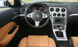 Wnętrze Alfa Romeo 159 1.9 JTD z brązową skórzaną tapicerką, kierownicą i panelem środkowym.