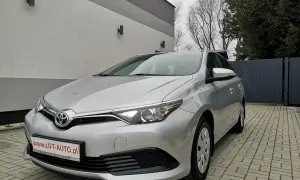 Srebrna Toyota Auris 1.6 benzyna zaparkowana na podjeździe z kostki brukowej.