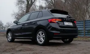 Czarna Skoda Fabia 1.0 TSI z tablicą rejestracyjną PY 5420E stoi na brudnym podjeździe, otoczona drzewami.
