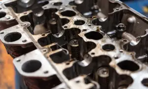 Metalowa głowica silnika z widocznymi sprężynami zaworowymi i otworami.