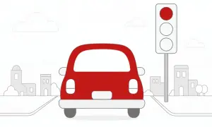 Czerwony samochód ignoruje czerwone światło na sygnalizatorze, jadąc przez miasto.