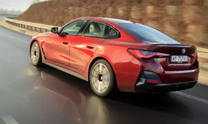 Czerwone BMW 4 Gran Coupé pędzi po zakręcie drogi, odbijając się w mokrej nawierzchni.