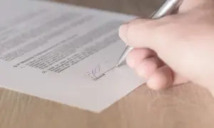 Dłoń podpisuje dokument, być może kartę pojazdu.
