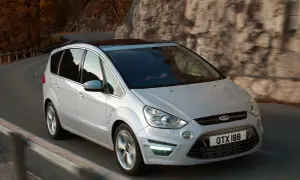 Biały Ford S-Max 2.0 TDCI na krętej drodze wśród jesiennych drzew i skał.