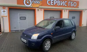 Ciemnoniebieski Ford Fusion 1.4 benzyna przed budynkiem serwisu gazowego.