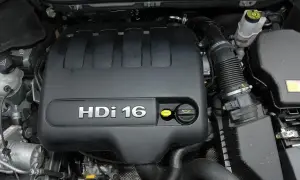 Silnik 2.0 HDi w Citroenie C5. Widoczna czarna pokrywa silnika z napisem "HDi 16" i żółte korki.