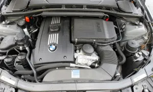 Silnik BMW 325i. Widok na pokrywę silnika z logo BMW, elementy układu dolotowego i chłodzenia.