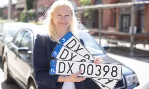 Kobieta trzyma tablice rejestracyjne z oznaczeniem DX. Nowe tablice dla Twojego auta, szybka dx rejestracja.