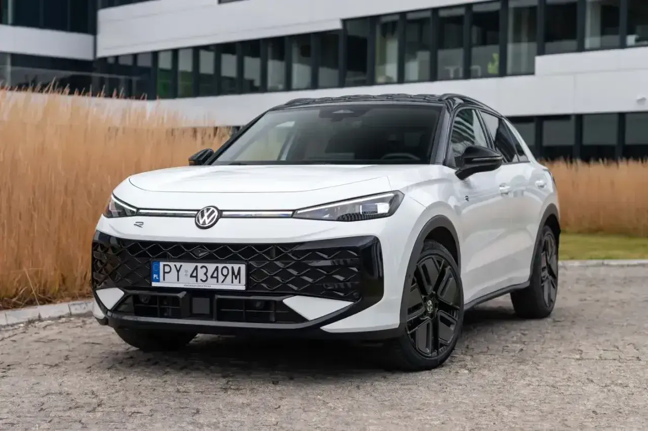 Biały Volkswagen ID.4, jeden z nowoczesnych volkswagen modele, zaparkowany przed budynkiem z przeszkloną fasadą.