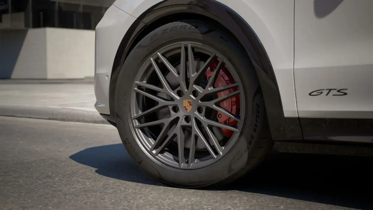 Zbliżenie na koło Porsche Cayenne GTS z czerwonymi zaciskami hamulcowymi i felgą w ciemnym kolorze.