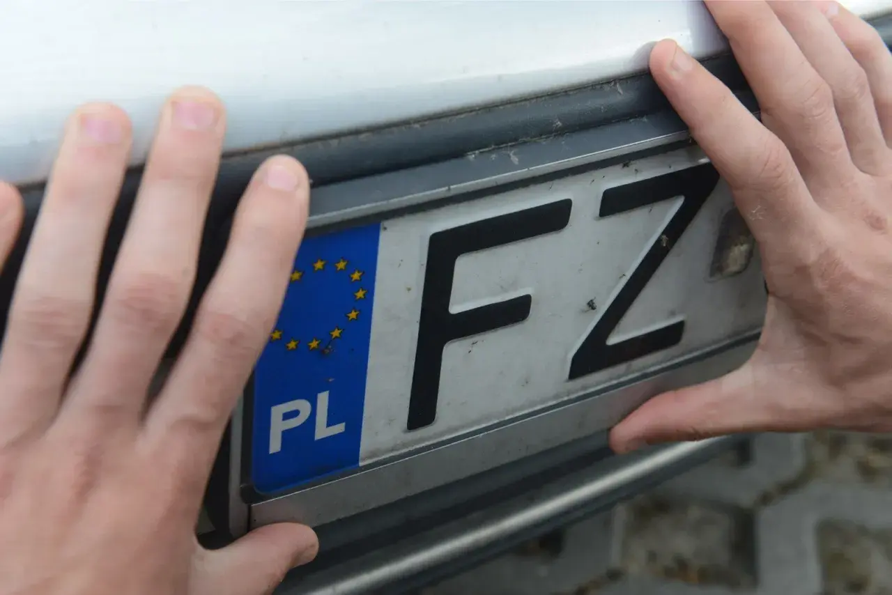 Dwie dłonie trzymają polską tablicę rejestracyjną z literami FZ. To ważny krok w procesie pwa rejestracja.