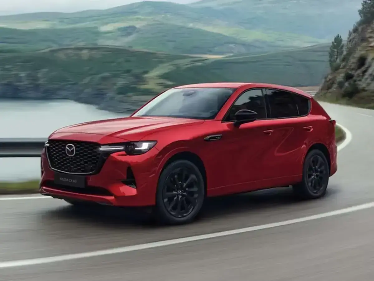 Czerwona Mazda CX-60 3.3 diesel na krętej drodze z widokiem na góry i jezioro.