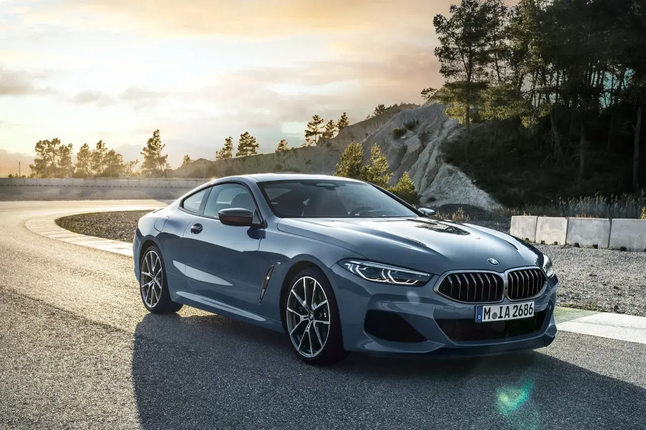 Eleganckie BMW 840i na zakręcie toru wyścigowego, z malowniczym krajobrazem w tle.