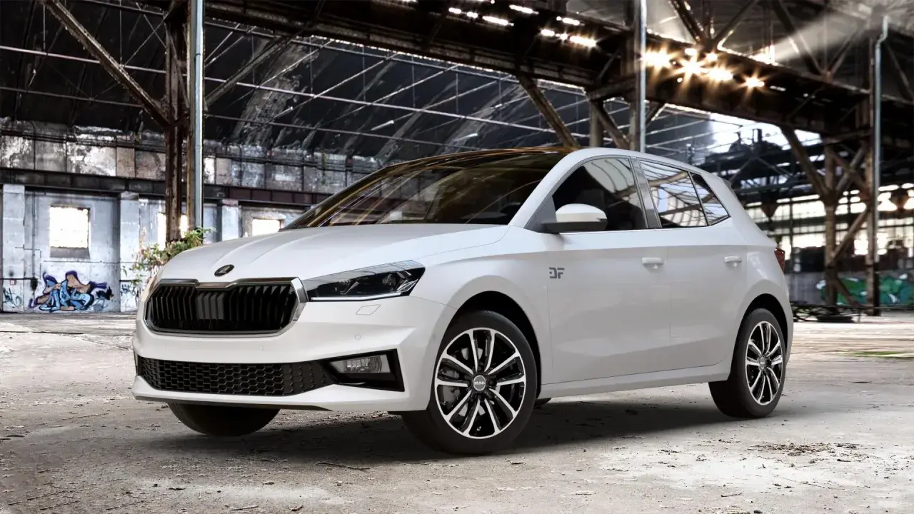 Biała Skoda Fabia Monte Carlo z czarnym dachem i felgami stoi w opuszczonej hali przemysłowej z graffiti.