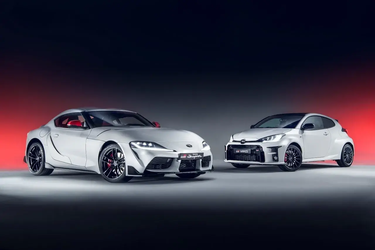 Dwa białe, sportowe japońskie auta: Toyota Supra i GR Yaris, prezentują swoją moc i styl.