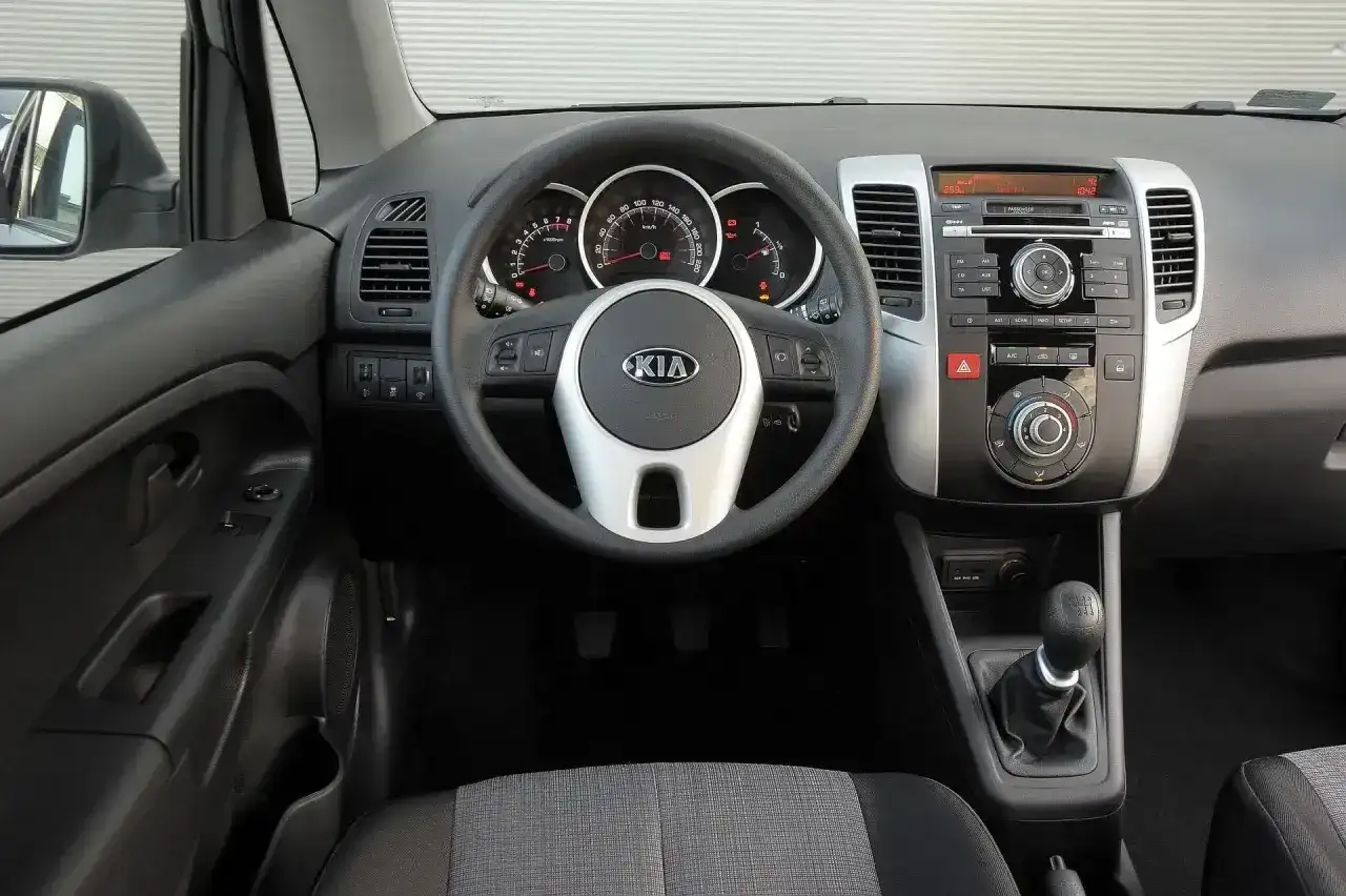 Wnętrze Kia Venga 1.4 benzyna: kierownica z logo Kia, deska rozdzielcza z radiem i nawiewami, dźwignia zmiany biegów.