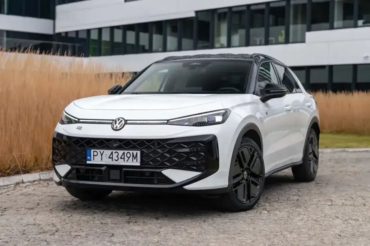 Biały Volkswagen ID.4, jeden z nowoczesnych volkswagen modele, zaparkowany przed budynkiem z przeszkloną fasadą.