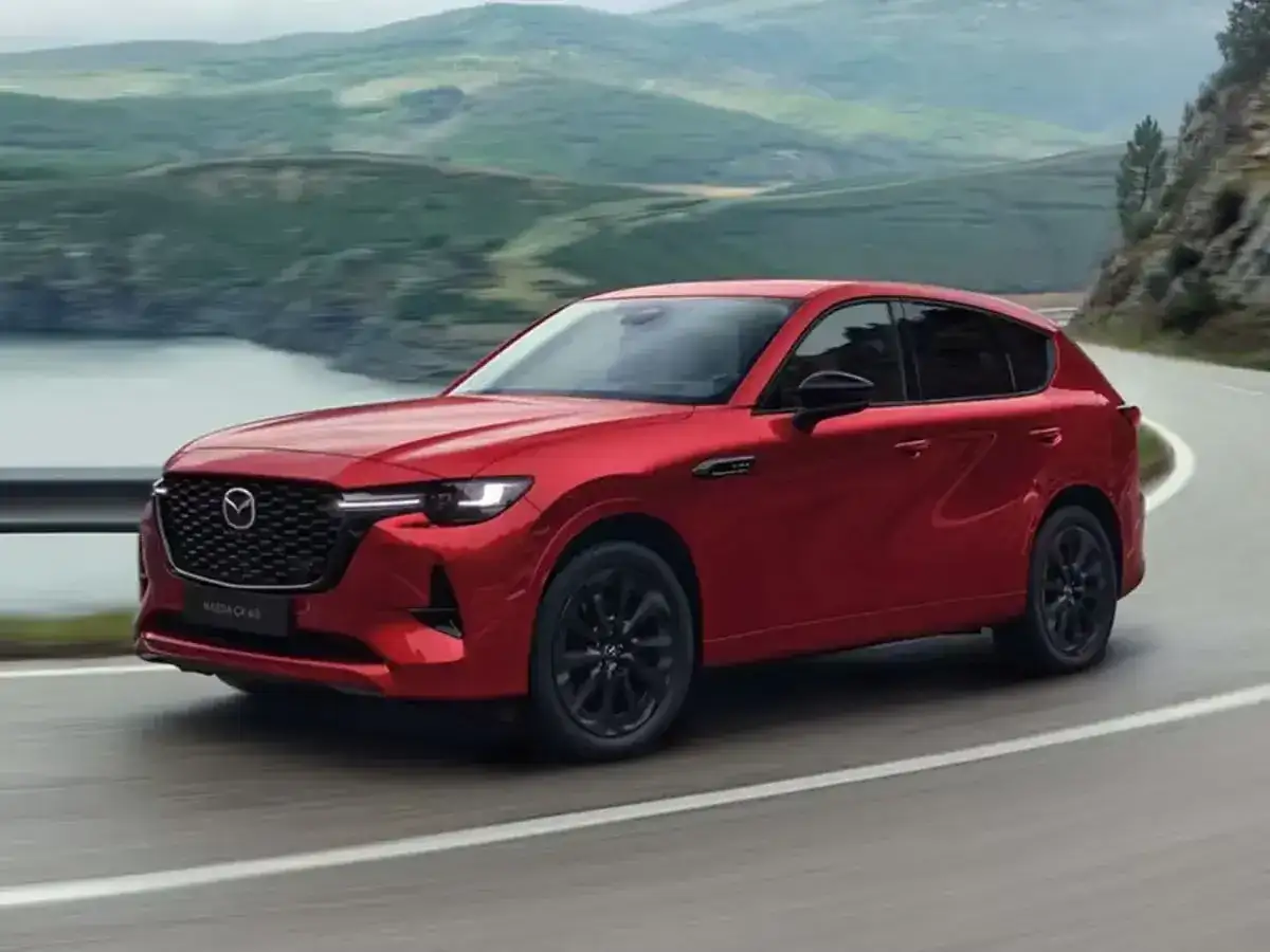 Czerwona Mazda CX-60 3.3 diesel na krętej drodze z widokiem na góry i jezioro.