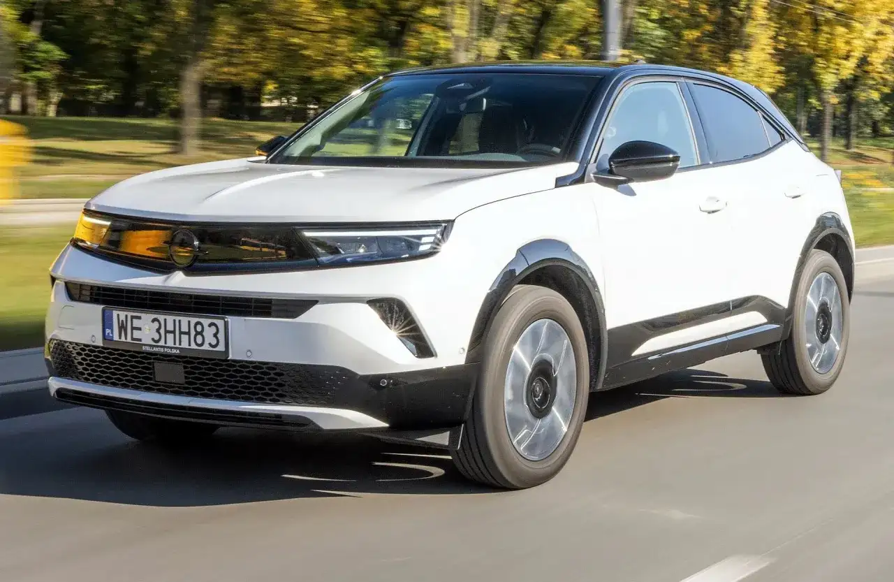 Biały Opel Mokka z czarnym dachem jedzie po drodze. Sprawdź atrakcyjną opel mokka cena!