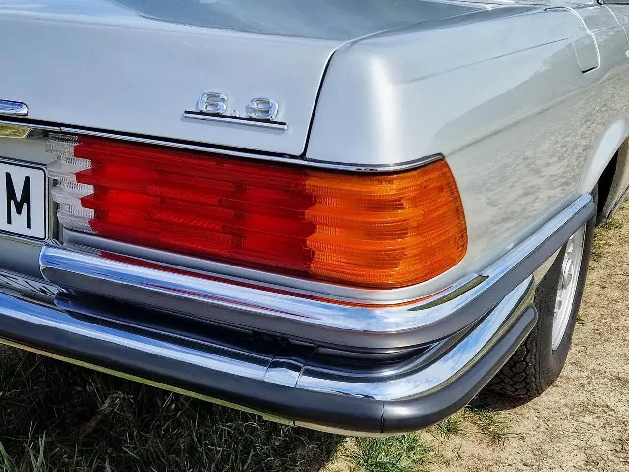 Srebrny Daimler 6.9 z chromowanymi zderzakami i charakterystycznymi czerwonymi i pomarańczowymi światłami tylnymi.