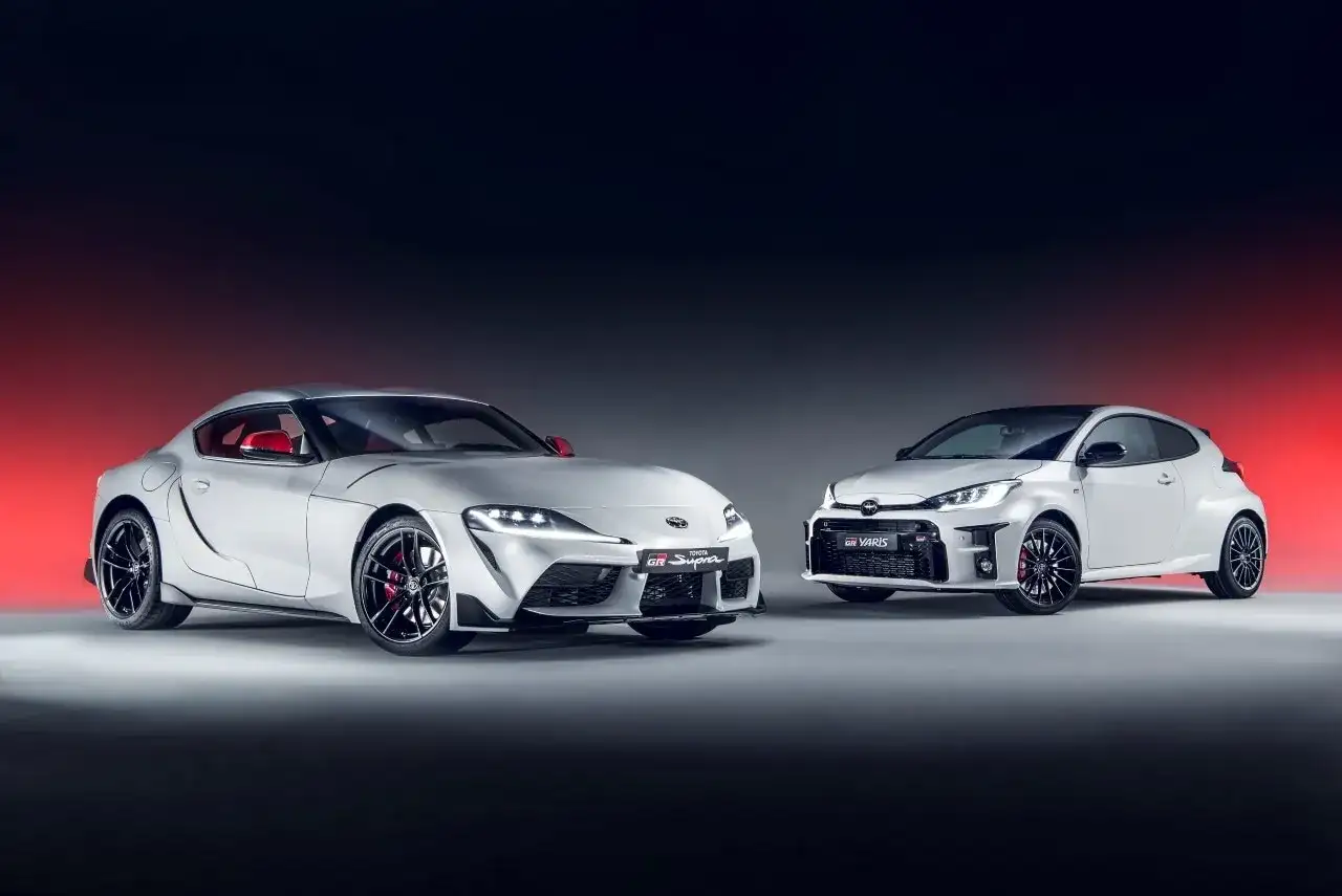 Dwa białe, sportowe japońskie auta: Toyota Supra i GR Yaris, prezentują swoją moc i styl.