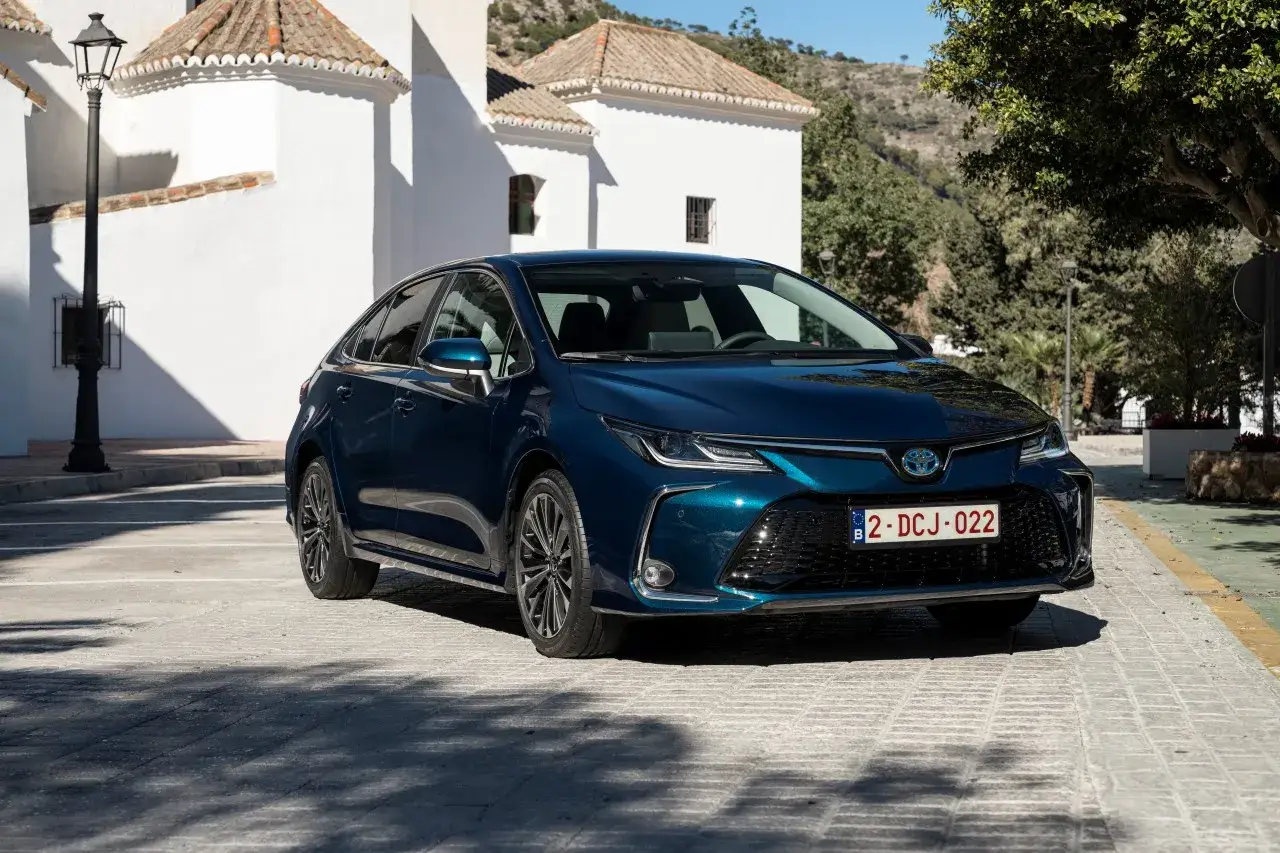 Elegancka, ciemnoniebieska Toyota Corolla na tle białych budynków. Sprawdź aktualną toyota corolla cena!