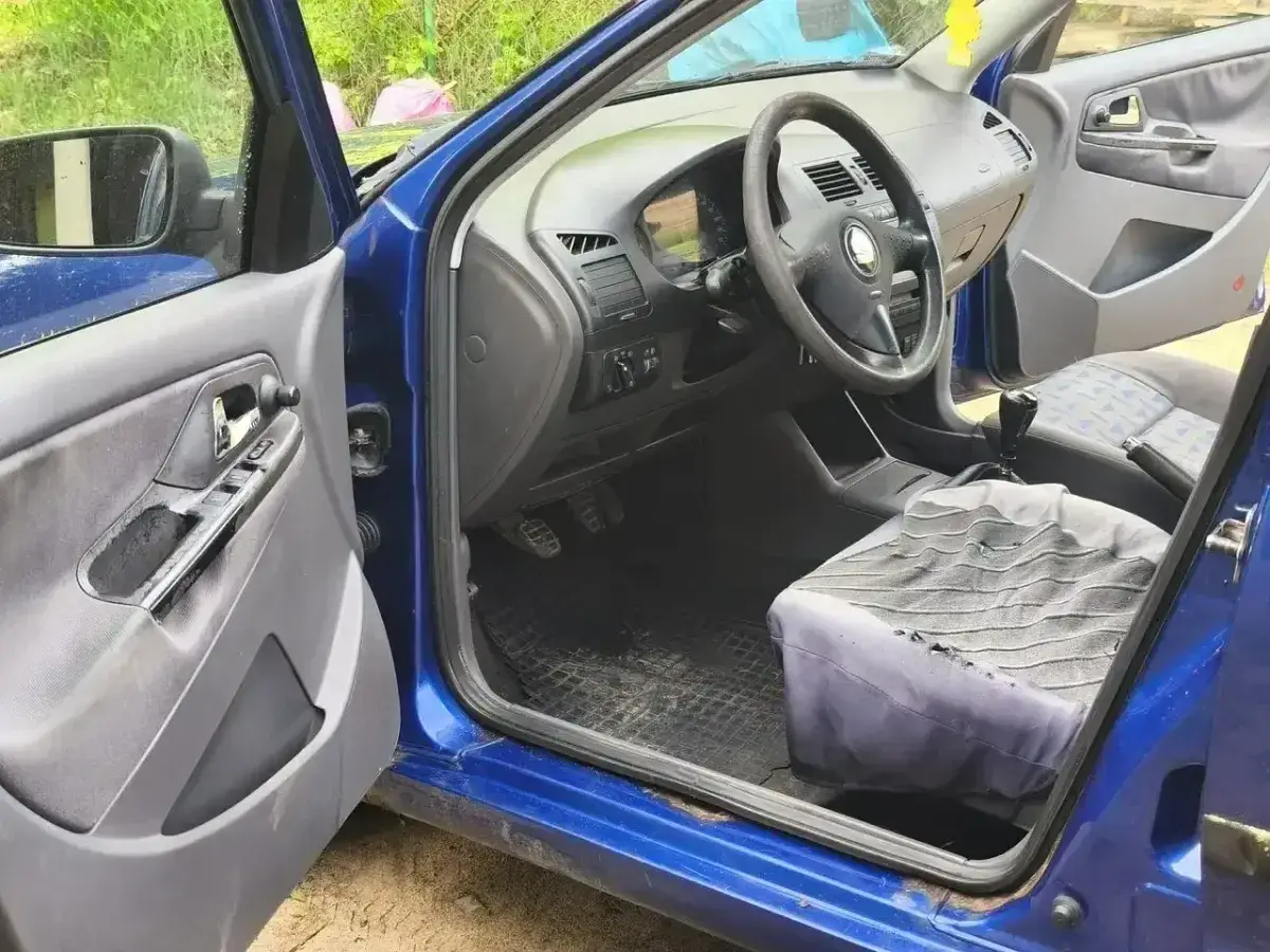 Wnętrze niebieskiego Seat Cordoba z przetartym siedzeniem pasażera i widocznymi elementami deski rozdzielczej.