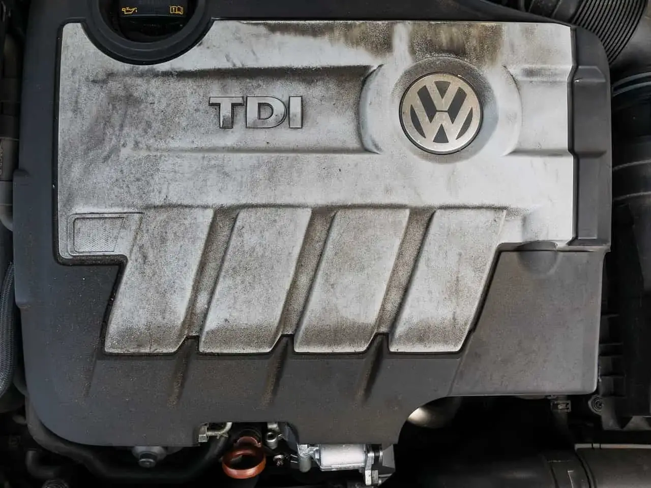 Pokrywa silnika TDI Volkswagena, z widocznym logo i śladami użytkowania.