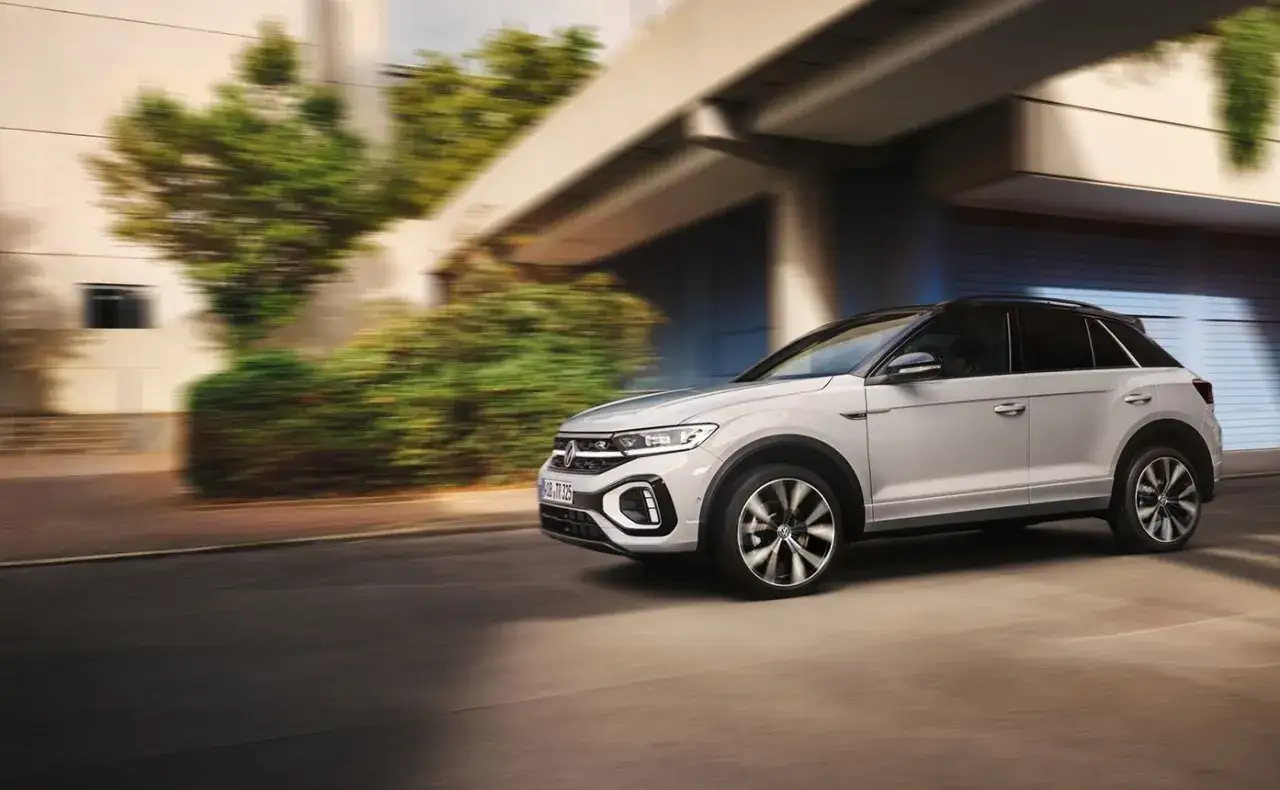 Biały Volkswagen T-Roc w ruchu miejskim. Ten model to jeden z wielu stylowych volkswagen modele.