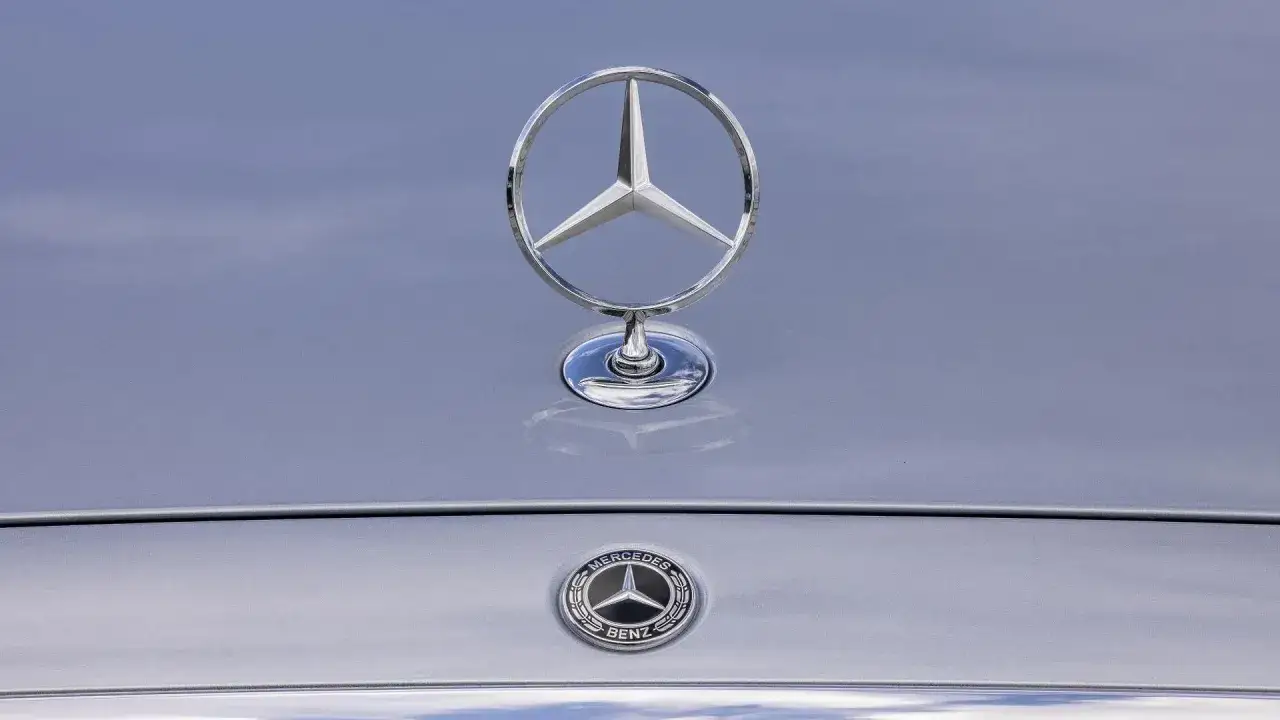 Błyszczące logo Mercedes-Benz na masce samochodu, symbol innowacji i dziedzictwa Daimler.