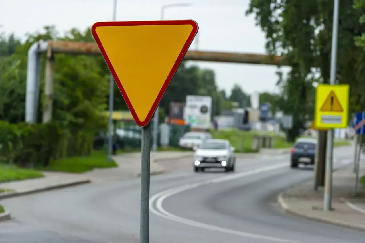 Znak A7 ustąp pierwszeństwa. Żółty trójkąt z czerwoną obwódką ostrzega kierowców o konieczności ustąpienia drogi pojazdom nadjeżdżającym z prawej strony.