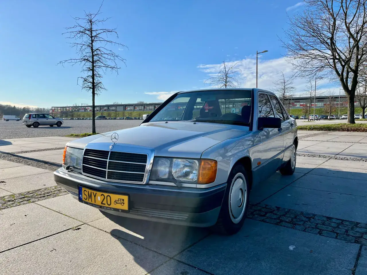 Srebrny Mercedes W190 z polskimi tablicami rejestracyjnymi SMY 20 zaparkowany na placu.