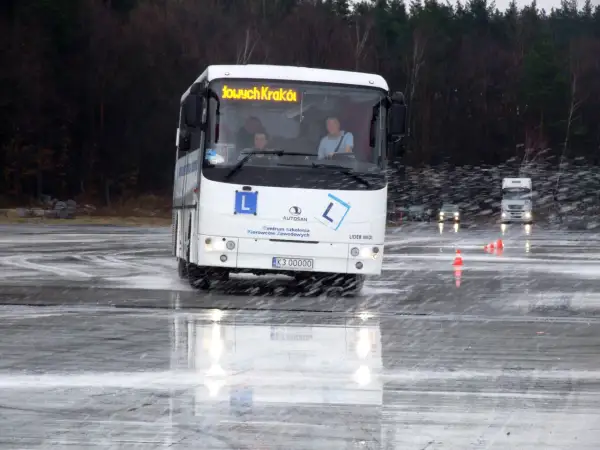 Autosan Lider Midi na mokrym placu manewrowym, z widocznymi kierowcami w kabinie.