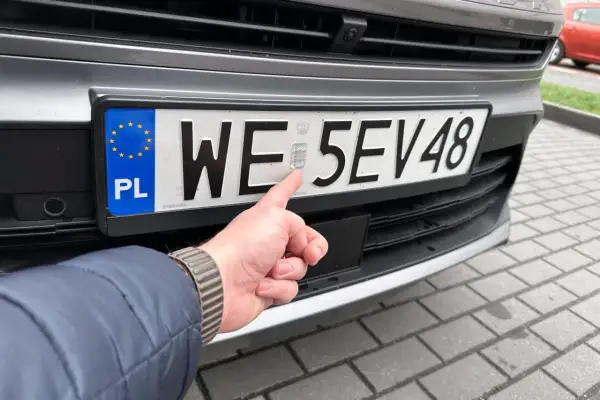 Palec wskazuje hologram na tablicy rejestracyjnej auta. Cały proces rejestracji auta zakończony sukcesem.