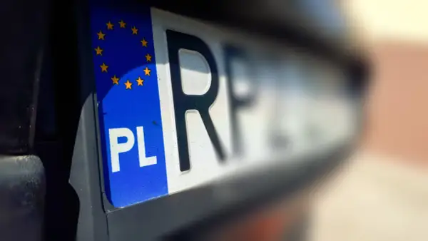Zbliżenie na polską tablicę rejestracyjną z symbolem Unii Europejskiej. Litery "PL" i fragment kolejnych liter wskazują na zsl rejestracja.