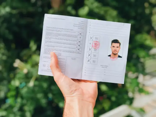 Międzynarodowe prawo jazdy z fotografią mężczyzny i pieczęciami. Dokument zawiera informacje o kategoriach pojazdów i wykluczeniach.