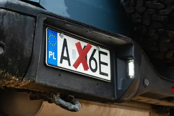 Polski numer rejestracyjny pojazdu AX6E z czerwoną naklejką na literze X.