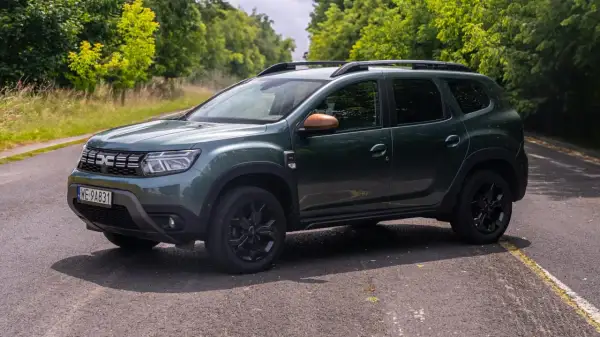 Zielony Dacia Duster 1.6 benzyna na tle zieleni.