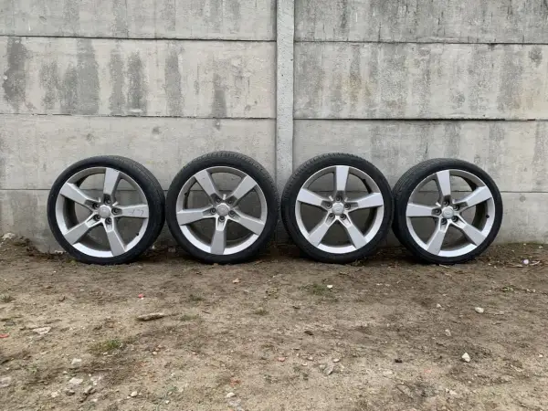 Cztery aluminiowe felgi z oponami Camaro SS na tle betonowego muru.
