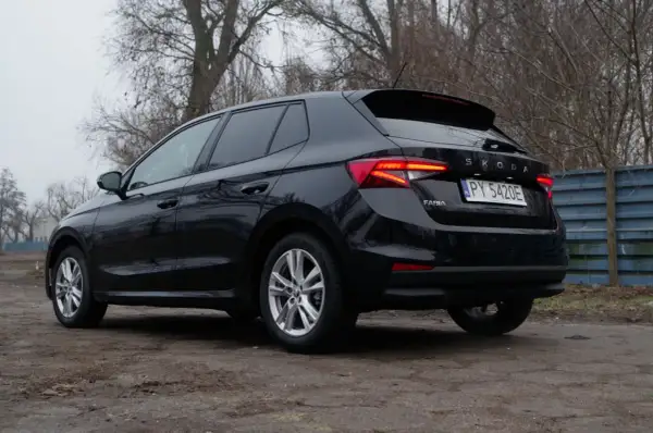 Czarna Skoda Fabia 1.0 TSI z tablicą rejestracyjną PY 5420E stoi na brudnym podjeździe, otoczona drzewami.